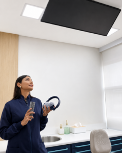 A doutora liga a TV no teto com o controle e prepara o fone com cancelamento de ruído